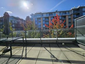 Vancouver apartment for rent - A balcony with a table and chairs overlooking a building and trees.