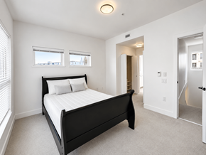 Burnaby apartment for rent - A bedroom with a large bed and a carpeted floor.
