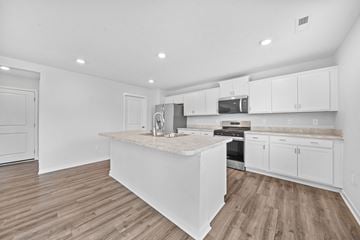 Lithopolis house for rent - A kitchen with white cabinets and a wooden island.