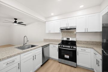 West Covina apartment for rent - A modern kitchen with white cabinets and a black stove top oven.