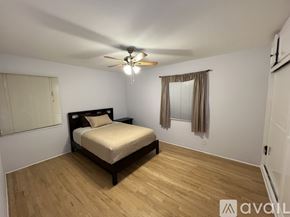 Hemet apartment for rent - A bedroom with a bed, wooden floors, and a ceiling fan.