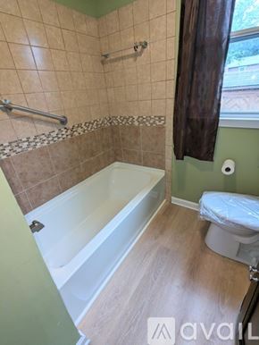 Nashville house for rent - A bathroom with a tub, toilet, and a window with a brown curtain.