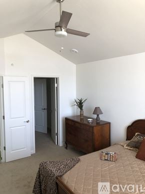 Waukesha apartment for rent - A bedroom with a bed, a nightstand with a plant, and a ceiling fan.
