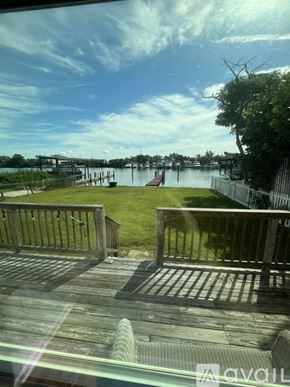 Tarpon Springs house for rent - A view from a window looking out to a dock with a boat and a fence.