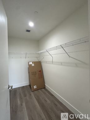 Oakland Park apartment for rent - A cardboard box sits on the floor of a room with a shelf on the wall.