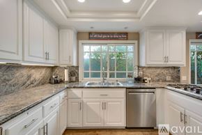 Huntington Beach house for rent - A kitchen with white cabinets and a marble countertop.