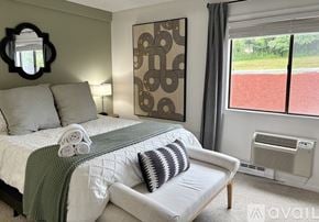 Laconia condo for rent - A bedroom with a bed, a couch, and a window overlooking a red area.