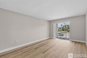 Fort Myers apartment for rent - A room with wooden flooring and a window overlooking a parking lot.