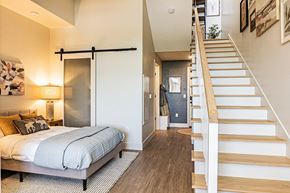 Garden City apartment for rent - A bedroom with a bed, a staircase, and a door.