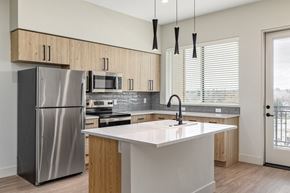 Garden City apartment for rent - A modern kitchen with a stainless steel refrigerator and wooden cabinets.