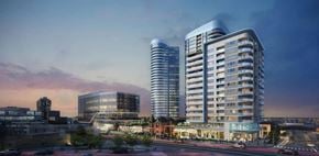 Kitchener apartment for rent - A modern building with a curved glass facade stands tall among other buildings.
