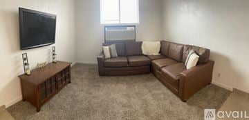 Bullhead City apartment for rent - A living room with a brown couch and a television mounted on the wall.