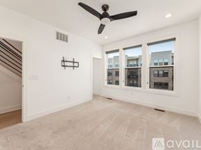 Columbus house for rent - A spacious room with a fan, carpet, and large windows.