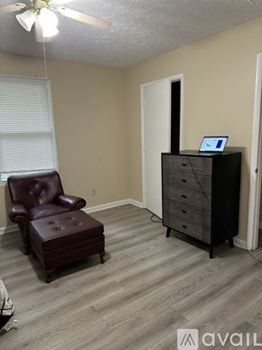 Nashville apartment for rent - A room with a brown leather chair and a black dresser with a laptop on top.