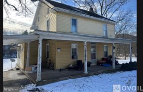 Mifflin house for rent - A yellow house with a porch and snow on the ground.