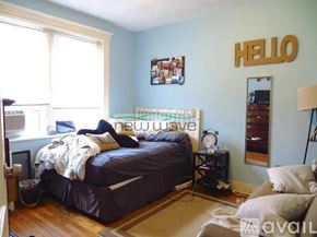 Boston apartment for rent - A bedroom with a bed, nightstand, and a wall hanging that says "HELLO".