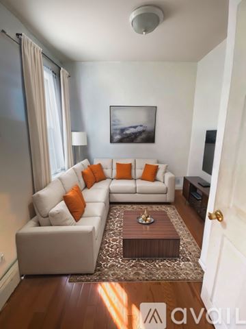 Boston apartment for rent - A living room with a white couch and orange pillows.