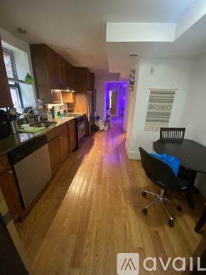 Boston apartment for rent - A kitchen with wooden floors and a dining area with a table and chairs.