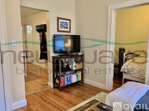 Boston apartment for rent - A living room with a television, a bookshelf, and a bed.
