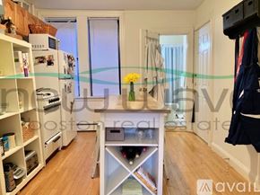 Boston apartment for rent - A kitchen with a refrigerator, oven, and a dining table with chairs.