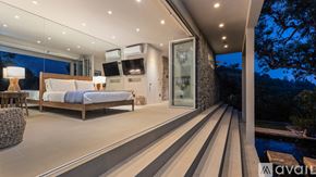 Los Angeles house for rent - A modern bedroom with a large bed and a balcony overlooking a pool.