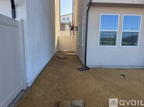 San Marcos house for rent - A sandy yard with a white fence and a door leading to another building.