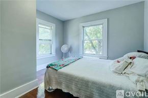 Irondequoit house for rent - A bedroom with a bed, a fan, and two windows.