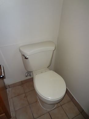Modesto house for rent - A white toilet with a white tank is in a bathroom with beige tiles.
