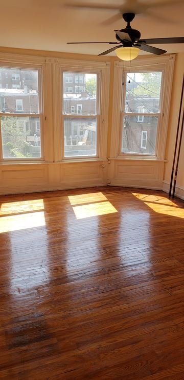 Philadelphia apartment for rent - A room with a ceiling fan and a window with a view of a building.