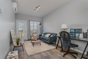 Saskatoon apartment for rent - A living room with a grey couch, a wooden coffee table, and a black chair.