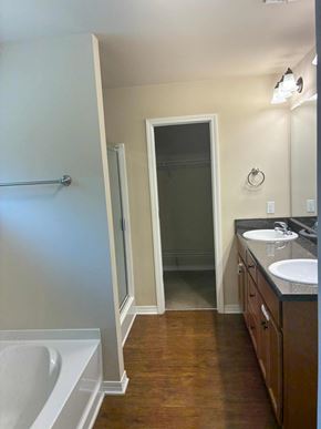 Mobile house for rent - A bathroom with a white tub, sink, and wooden floors.