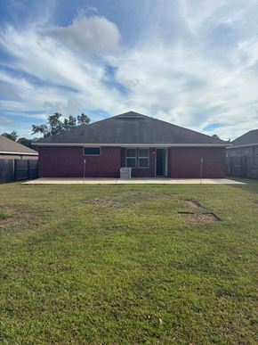 Mobile house for rent - A red brick building with a grey roof and a green lawn in front.
