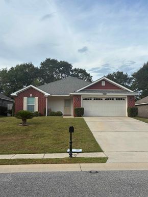 Mobile house for rent - A red brick house with a white garage door and a mailbox on the sidewalk.