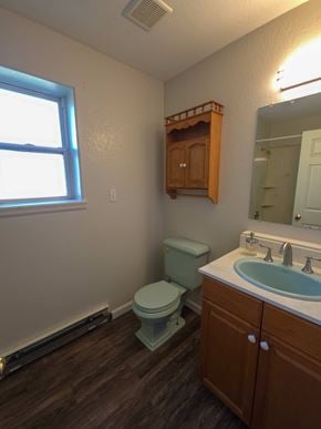 La Veta house for rent - A bathroom with a toilet, sink, and wooden cabinet.