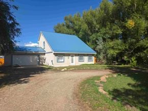 La Veta house for rent - A small house with a blue roof is surrounded by trees.