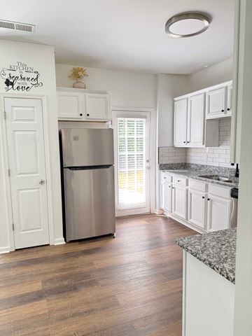 Hampton house for rent - A kitchen with white cabinets and a wooden floor.