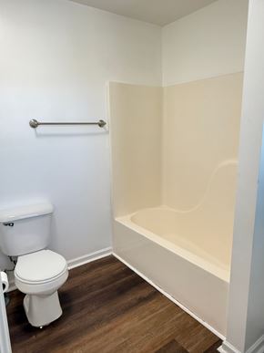 Hampton house for rent - A white toilet sits next to a bathtub in a small bathroom.