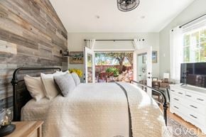 Buellton house for rent - A bedroom with a large bed and a wooden wall.