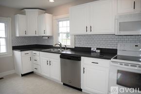 Berryville house for rent - A kitchen with white cabinets and black countertops.