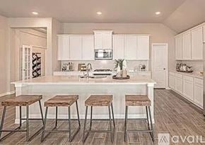 Garland house for rent - A kitchen with white cabinets and a center island with bar stools.