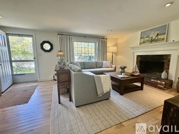 Brewster house for rent - A living room with a grey couch, a fireplace, and a painting on the wall.