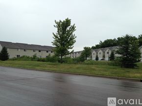 North Mankato townhouse for rent - A wet street with a tree and houses in the background.
