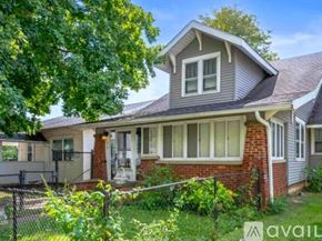 Muncie house for rent - A house with a grey roof and a white fence is for sale.