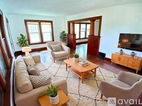 Muncie house for rent - A living room with a white couch, a grey armchair, a wooden coffee table, and a television.