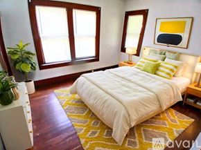 Muncie house for rent - A bedroom with a large bed and a yellow rug.