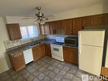 Des Plaines condo for rent - A kitchen with brown cabinets and a white fridge.