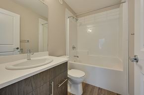 Edmonton apartment for rent - A white toilet sits in a bathroom with a white sink and a walk-in shower.