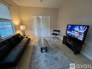 New Orleans townhouse for rent - A living room with a black sofa, a coffee table, and a television on a stand.