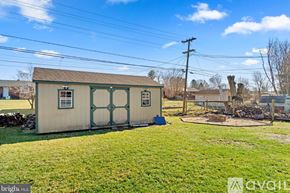 Hagerstown house for rent - A small building with a green door and a window is surrounded by a grassy area.