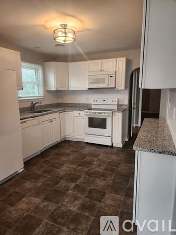 Hagerstown house for rent - A kitchen with white appliances and brown tiled flooring.